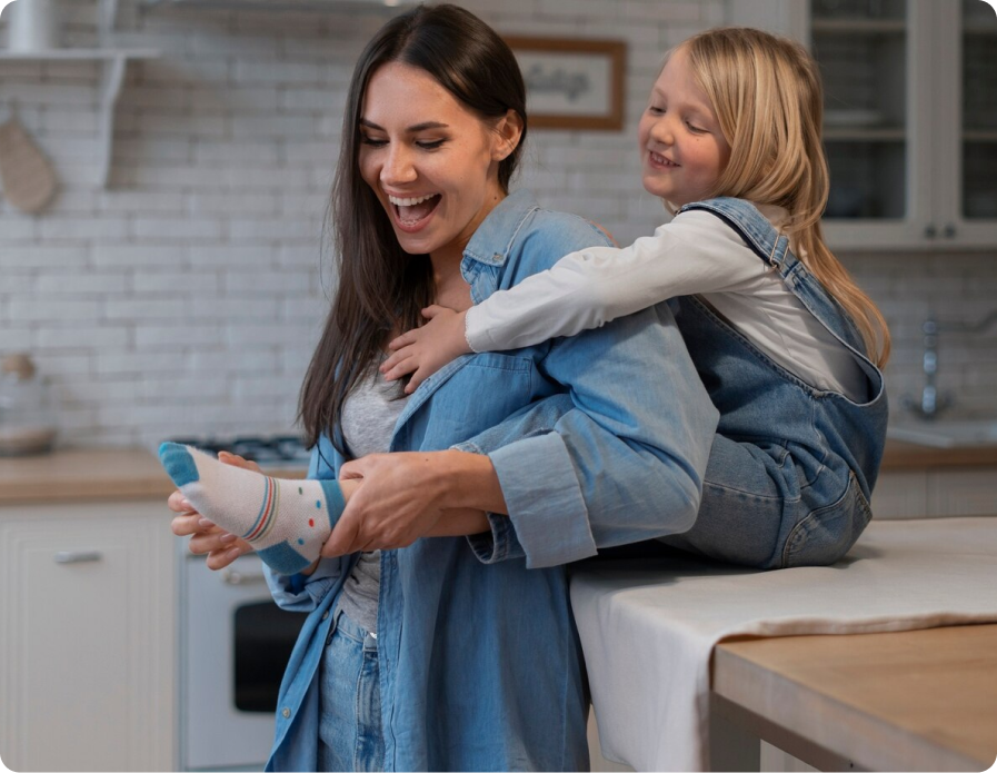 A mother and her daughter laughing together in the kitchen, creating a warm family moment.